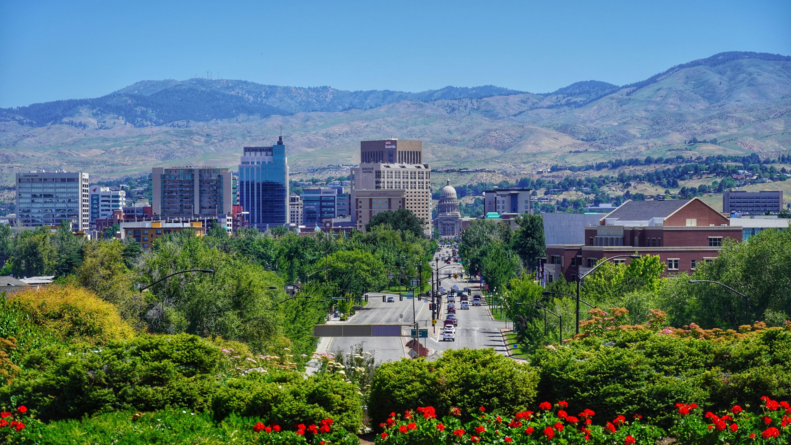 Wide angle shot of Boise showing trees, the city and mountains in the background with an open sky.