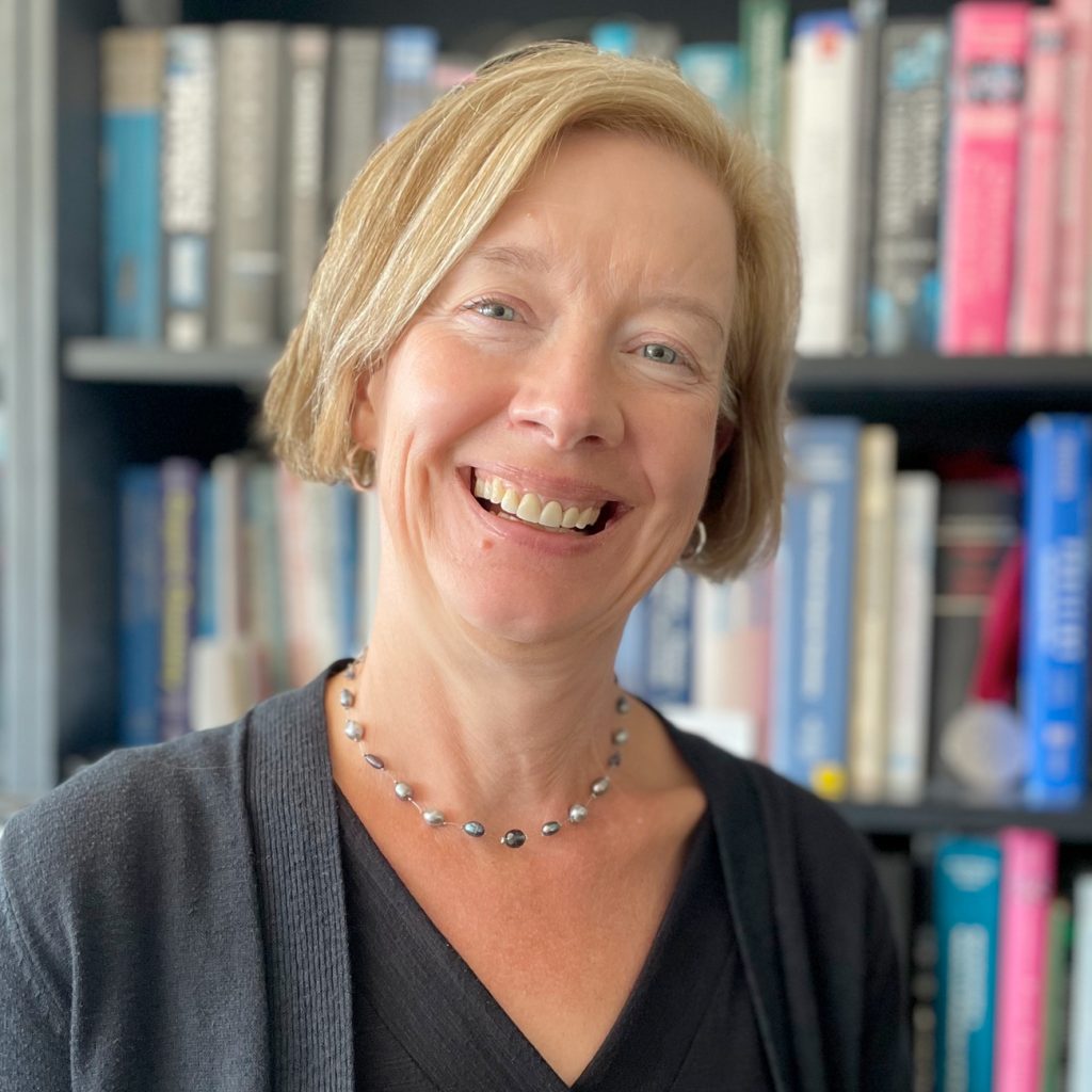 Helen Blackwell smiles in front of a full bookshelf
